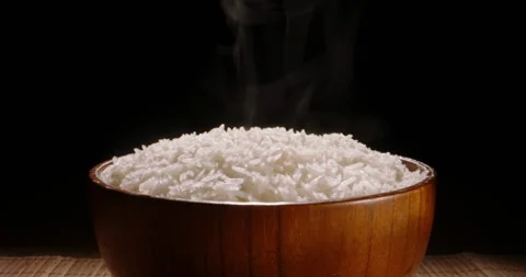 Hot white cooked rice steam bowl black background slow motion, Close up. Sticky 動画素材 243813664