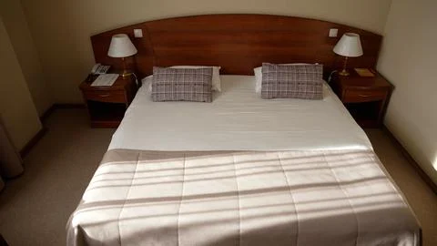 Hotel bedroom interior with empty bed and wooden furniture Stock Photos