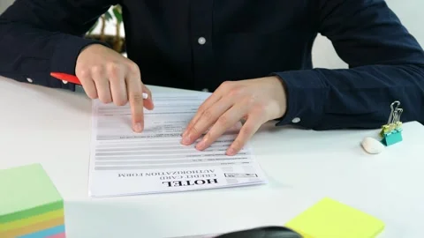 A hotel check-in form in front of a man who is reading it and trying to figure 스톡 동영상 313323748
