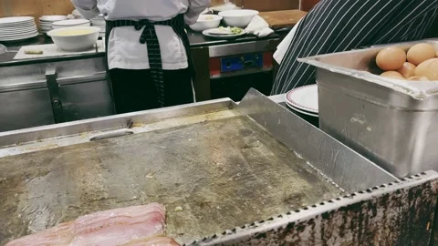 Hotel Chef cooking fried eggs and fried bacon in pan in kitchen. Stock Footage 233518138
