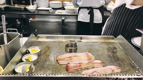 Hotel Chef cooking fried eggs and fried bacon in pan in kitchen. Breakfast . Stock-Footage 239258805