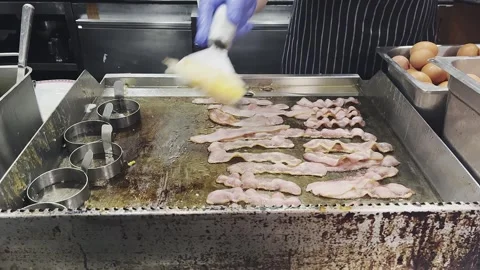 Hotel Chef cooking fried eggs and fried bacon in pan in kitchen. Stock Footage 282897811