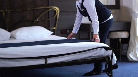 Hotel cleaner makes a double bed in a small, cozy hotel room. Slow motion. Stock Footage 101226583