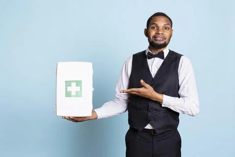 Hotel concierge doorman pointing at a first aid kit used for medical purposes Foto stock