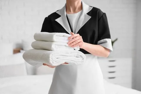 Hotel housekeeper holding stack of fresh white towels for room service and gu Stock Photos