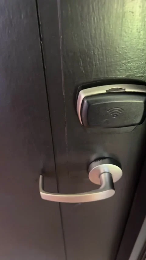 Hotel key card held against an electronic door lock, filmed from a guest’s Stock Footage 346411344