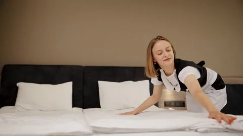 Hotel maid making the bed in a modern room, ensuring cleanliness and comfort Stock Footage 324721788