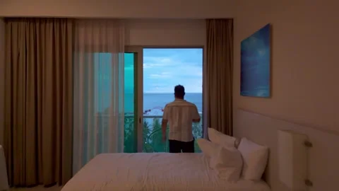Hotel Room with Ocean View at Sunset, Man Opening Curtains Stock Footage 318047796