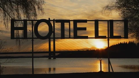 Hotel sign silhouette sunset while water jet passing by Video stock 131706476