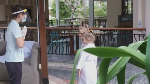 Hotel staff greets two cute sister kids wearing little bathrobes walking to spa Stock-Footage 139404684