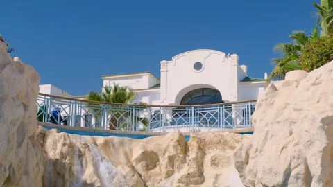 Hotel in white. View of the grounds, pool and tropical palm trees Stock Footage 240200032