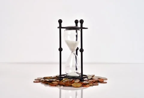 Hourglass and coins Stock Photos