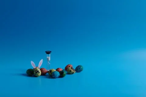 Hourglass and painted eggs for easter holiday on blue background Foto stock