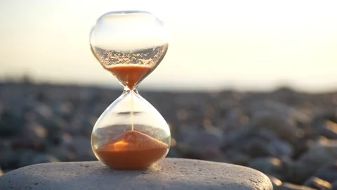 Hourglass on background of waves of the sea. time on sand and pebble stone Stock Footage 238526231