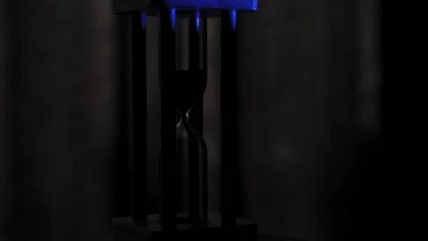 Hourglass close-up on a dark background. A spinning hourglass illuminated by Stock Footage 167585123