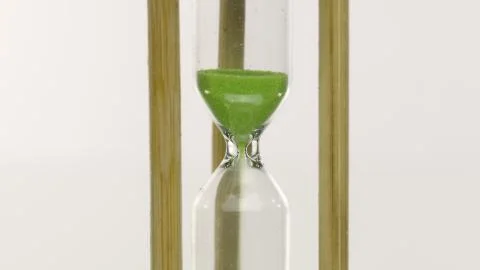 Hourglass countdown isolated on white background. Green sand falling, time over Stock Photos