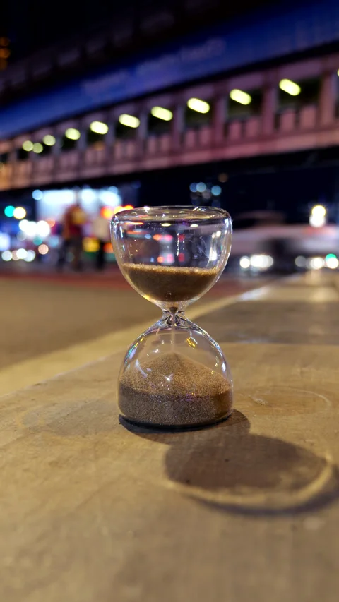 Hourglass counting down time in bustling Bangkok street at night 스톡 동영상 326383363