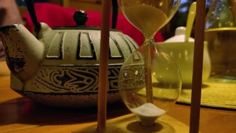 Hourglass Measuring Tea Brewing Time Beside Teapot in Cozy Tea House Stock Footage 336671099