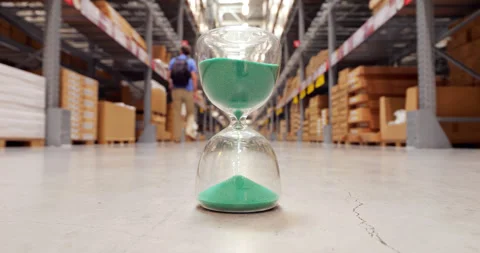 Hourglass measuring time passing in warehouse, man stroll by Stock Footage 319014886