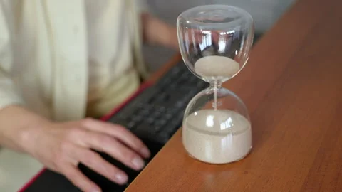 Hourglass measuring time passing while working on computer Видео 334784381