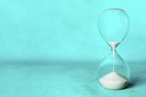 Hourglass with sand falling through, side view on a vibrant blue background with Foto stock
