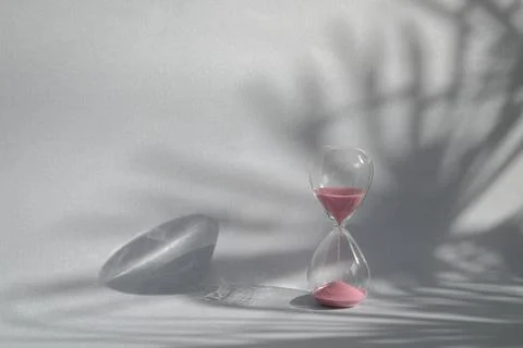 Hourglass sand timer with palm shadow on wall. Stock-Fotos