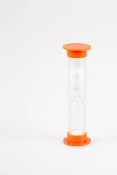Hourglass timer in plastic orange in grey background with white sand Foto stock