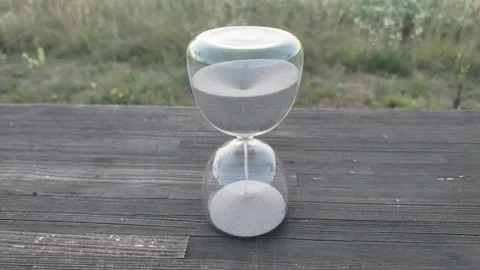 Hourglass timer with sand flowing on weathered wooden planks outdoors Stock Footage 340631345