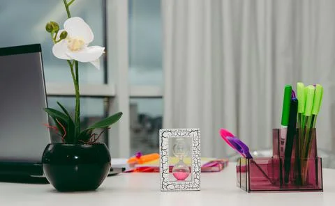 Hourglass on the work table, work table with flower and pens Foto stock