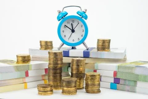 Hours cost on a pack of notes, around there are stacks of coins Stock Photos