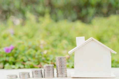 House and stack coins on blurred green natural background. Property investmen Stock Photos