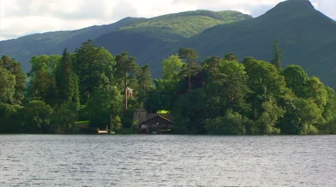 House and trees on the other side of the lake, mountains in background Stock Footage 39994599