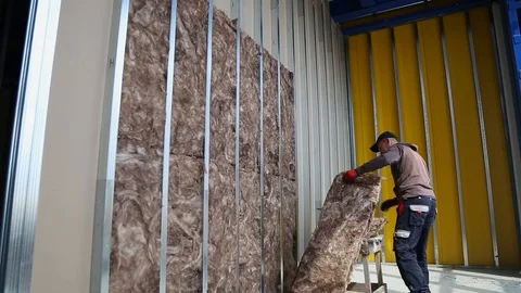 House attic insulation - construction worker installing rock wool in mansard Stock Footage 128497050