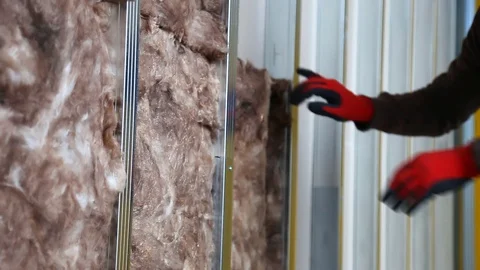 House attic insulation - construction worker installing rock wool in mansard Stockbeeldmateriaal 128497159