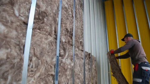 House attic insulation - construction worker installing rock wool in mansard Stockbeeldmateriaal 128497215