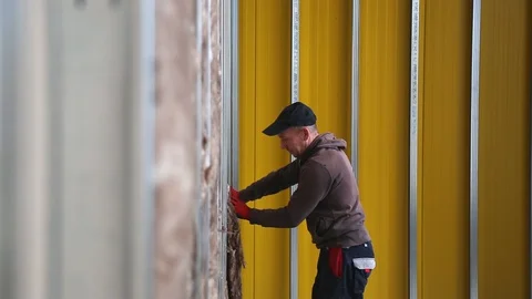 House attic insulation - construction worker installing rock wool in mansard Stockbeeldmateriaal 128497280