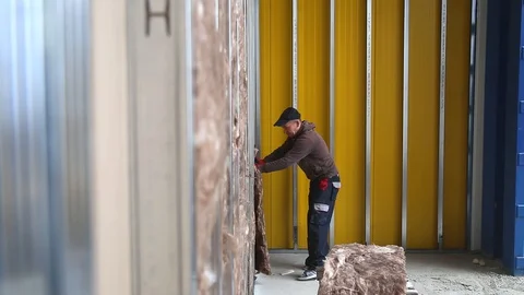 House attic insulation - construction worker installing rock wool in mansard Stockbeeldmateriaal 128497371