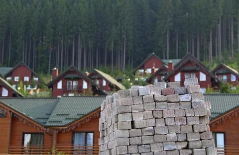 House Construction. Square Bricks Stacked In Front Of Wood Cottages Stockfoto's