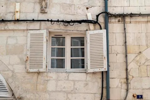 House facade with old window and wooden roller shutter with power line Stock Photos