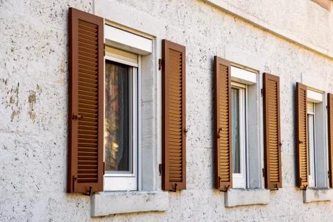 House facade with two windows with old wooden shutters with slats Stock Photos