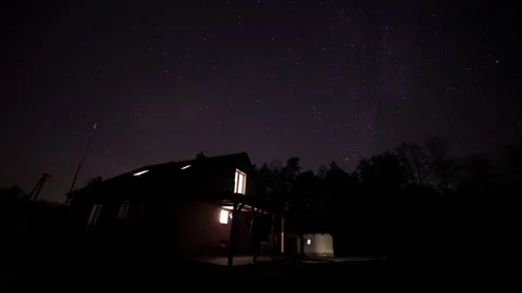 House in forest under starry night sky in 4k time lapse. Spooky atmosphere. Stock Footage 164828051