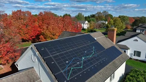 House with a full array of solar panels, amidst fall foliage. Animation of Stock Footage 271729569