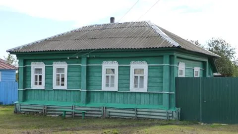 The house is green with carved window frames and a slate roof. Foto stock