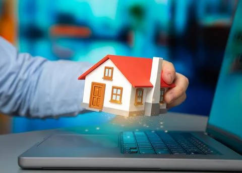 A house in the hands of a programmer symbolizes digital property management.. Stock-Fotos