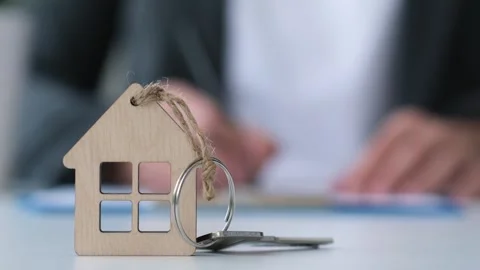 House key and blurred client signing mortgage loan agreement on background Stock Footage 253688265