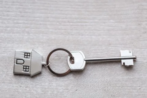 House key and keychain in the form of homes lies on wooden boards. Concept for Stock Photos