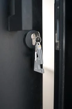 A house key with a key ring inserted at the door lock. Buy new home or concep Stock Photos