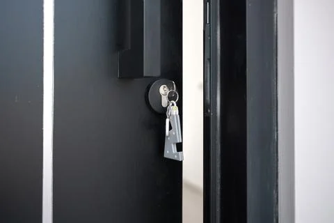 A house key with a key ring inserted at the door lock. Buy new home or concep Stock Photos