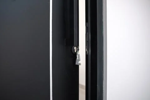 A house key with a key ring inserted at the door lock. Buy new home or concep Stock Photos