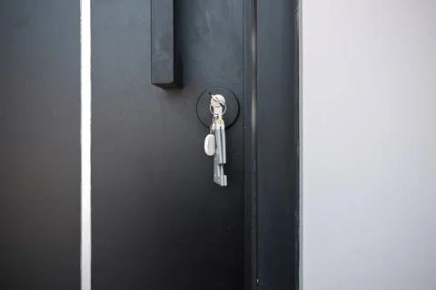 A house key with a key ring inserted at the door lock. Buy new home or concep Stock Photos